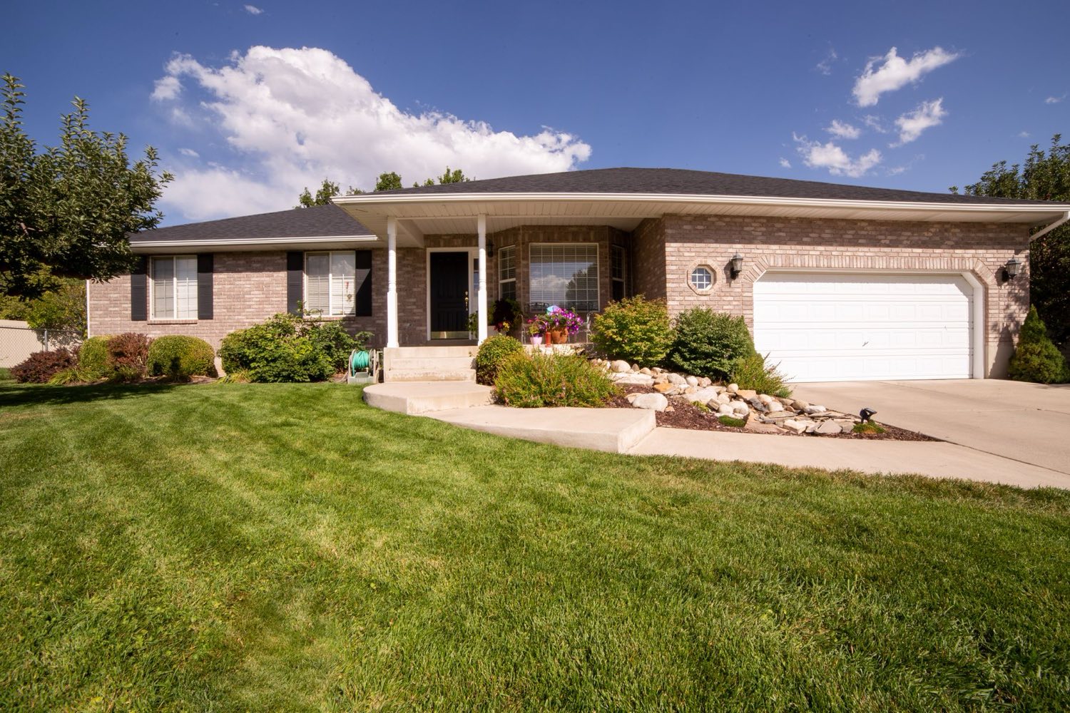 Brick ranch home with a curved concrete driveway and green lawn